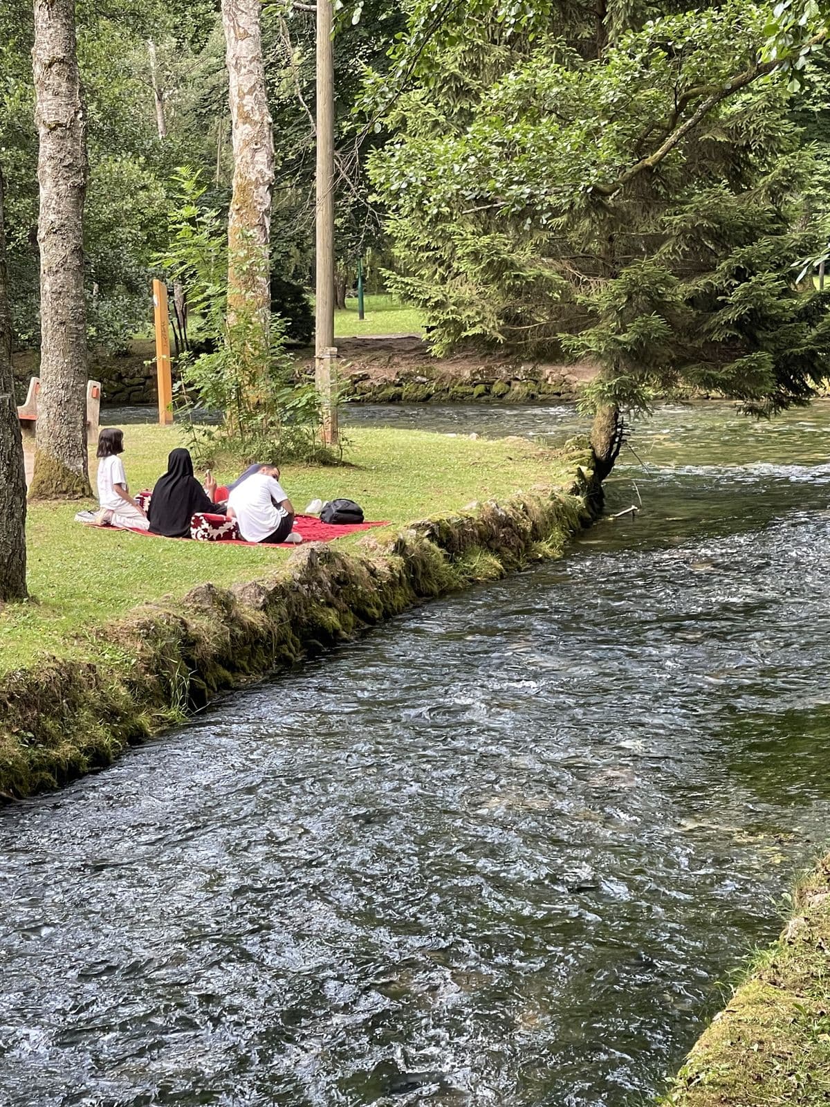 Family relaxing beside a clear Bosnian river on a halal-friendly tour